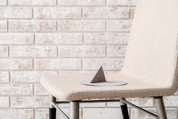 Thumbtack on chair near brick wall. Hemorrhoids concept