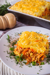 Delicious potato casserole with meat and cheese on a white wooden background