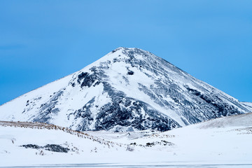 Fototapeta na wymiar Single dramatic symetrical volcanic,snow covered cone near lake Myvatn, Iceland in mid winter