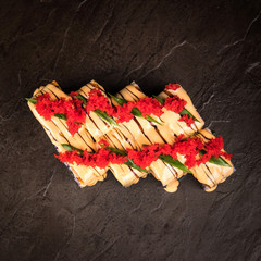 Japanese style rolls decorated with tobiko sauces and caviar top view