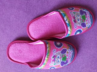 Beautiful children colorful indoor slippers on a purple background.