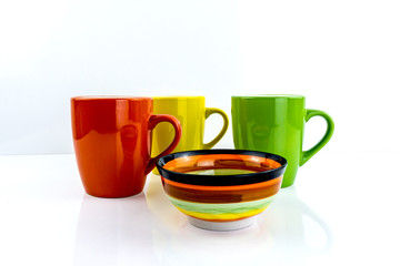 Porcelain cups of different colors stand on a white background.