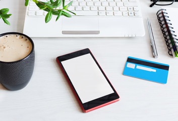 Smartphone blank screen and credit card on white wooden office table. Online shopping concept.