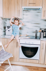 Little girl is cooking while quarantine and self-isolation. A kid playing with flour in the kitchen.