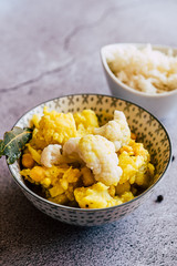 Curry de légumes avec des patates chou-fleur et pois chiche avec un bol de riz