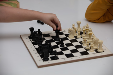 sits at a table and plays chess. The kid concentrated on the game and thinks where to make his next move. Early development, home educational games for children