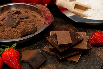 grated chocolate in a bowl, pieces of bittersweet and milk chocolate, flour and strawberries