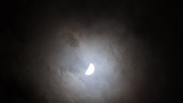 vid&eacute;o en temps r&eacute;el d'un satellite passant devant le centre de la lune derri&egrave;re les nuages