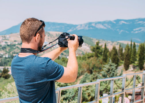 Man holding camera in his hands and making photos of the mountains
