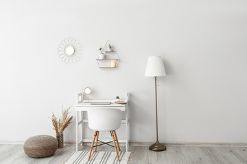 Stylish workplace near white wall in room