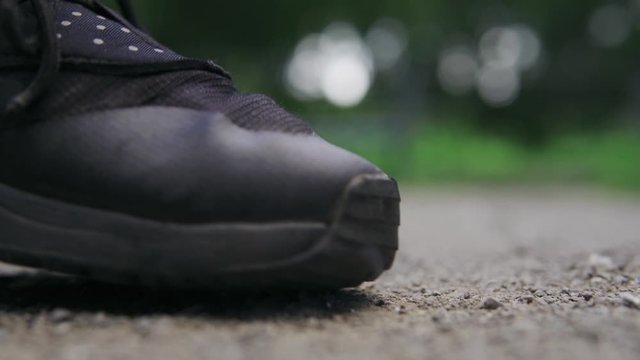 Man crushes burning cigarette with his foot outdoor in park. No smoking concept