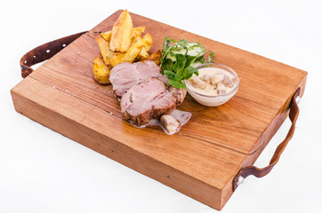 Fried pork neck with potato..gratin and creamy mushroom sauce on a wooden board