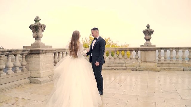 the bride runs to the groom, in the square of the old castle, the landscape of the old town white background, long light hair. Balinese residence and balusters 
palace. Slow motion.