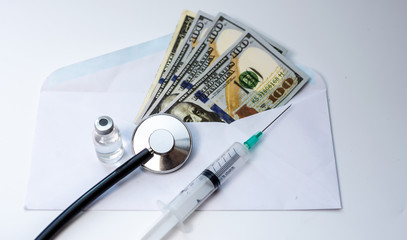 A dollar bill and stethoscope with syringe is inserted into the bill. The concept is the fall of the economy. Inflation, covid-19 pandemic, Health care cost concept