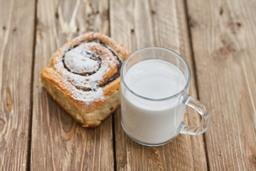 Basket of homemade buns with jam, served on old wooden table with cup of milk