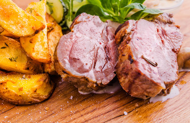 Fried pork neck with potato..gratin and creamy mushroom sauce on a wooden board