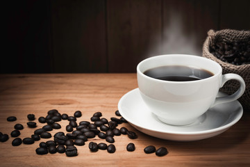 Wooden table desk with coffee. Coffee beans and coffee cup on wooden background with copy space.