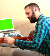 Young man tuning the guitar at home.