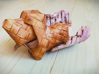 A toy dog made of birch bark stands on a green wooden floor.