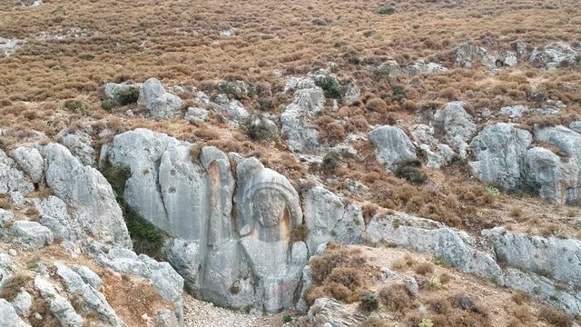 forward flight towards the huge statue of charon engraved on a rock at st. pierre church location, antakya, turkey