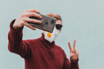 A man in a protective mask takes a selfie picture of himself, talks via video link. The concept of protection and disinfection in times of viruses.