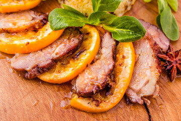 Juicy stewed duck breast in the company of turmeric with prunes, dried apricots and orange sauce on a wooden board