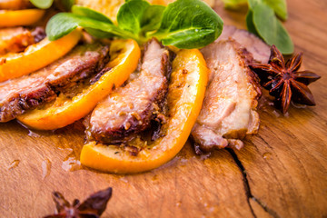 Juicy stewed duck breast in the company of turmeric with prunes, dried apricots and orange sauce on a wooden board