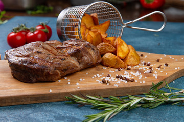 steak and potato wedges on a wooden plate