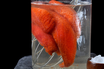 Red caviar in egg sack in a glass jar. Process of salting caviar 