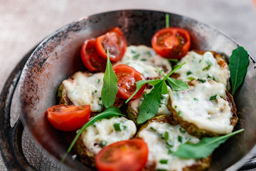 Pan-fried zucchini with garlic sauce and cherry tomatoes. Next to arugula, napkins, fork and mayonnaise. A colorful appetizer dish in a rustic setting