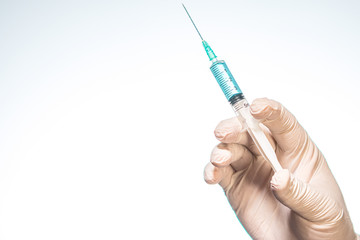 Hand wearing latex glove holding syringe with a medicine on white background