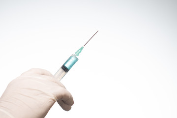 Hand wearing latex glove holding syringe with a medicine on white background
