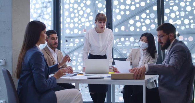 Caucasian woman, head of company department rulling at business partners meeting. Female boss leading at company employees talk and checking work of staff. Co-workers report concept.