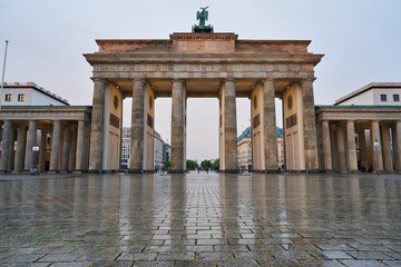 berlin germany, deserted brandenburg gate with reflections on the wet asphalt and with clouds. special perspective as close-up from the ground, tv tower and town hall in the background © Peter Jesche