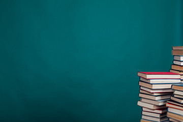 many stacks of educational books for exams at the university in the library on a green background