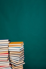 many stacks of educational books for exams at the university in the library on a green background