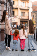 Happy family. mother of many children and three daughters child girl together, walking and joyfully laughing while relaxing on park on a summer holiday. Family outdoors lifestyle. Back view