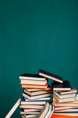 many stacks of educational books for exams at the university in the library on a green background