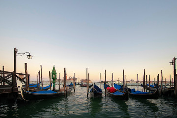 Naklejka premium Several gondolas moored nearby Saint Mark square, early morning, tranquil sunrise atmosphere, usually serving tourists for transportation around the narrow canals, in Venice, Italy