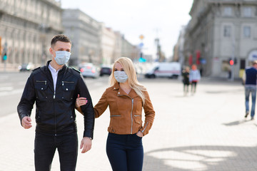 Young couple in masks on city street.