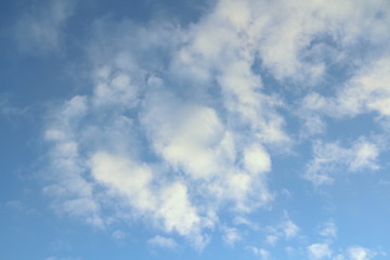 Clouds in the blue sky at sunset or dawn backlit by the sun. Place for text and design.