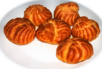 Hand baking, eclairs on a white dish.