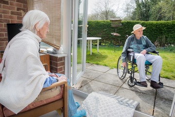 Elderly couple at home in the back garden enjoying nice weather,England,United Kingdom.