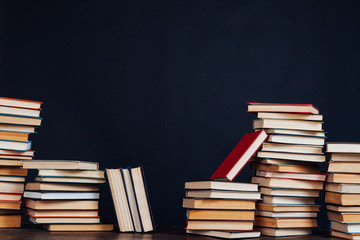 many stacks of educational books for college exams in the library on a black background