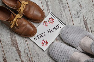 A man in slippers in front of brown shoes. The inscription Stay Home. Quarantine concept