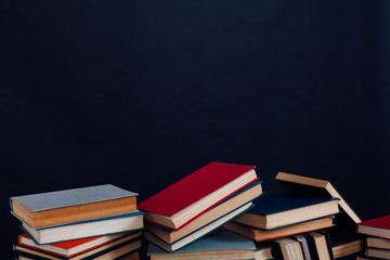 many stacks of educational books for college exams in the library on a black background
