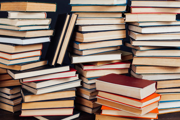many stacks of educational books for college exams in the library on a black background