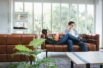 Couple Love Having Enjoy Relaxation on Sofa at Their Home, Attractive Asian Couple Happiness in Romantic Moments at Living Room While Reading Magazine and Work at Home. Relaxing and Lifestyles Concept