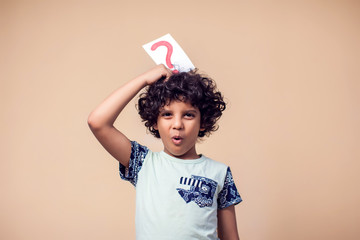 A portrait of kid boy holding cards with question mark. Children and education concept