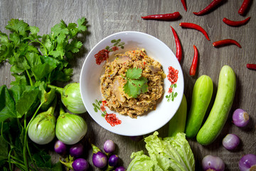 Top view of the Mackerel chili paste on a white plate with vegetables on a wooden table. Chili paste is a popular food for Thais and foreigners.